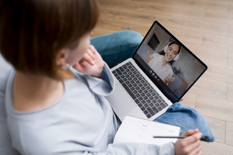 Mulher em sessão de terapia com psicólogo online pelo notebook, anotando orientações para melhorar a saúde mental